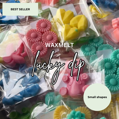 A close-up assortment of colorful wax melts in small clear plastic bags, featuring flower, heart, and animal shapes in pink, yellow, blue, and teal. White text overlays read 'BEST SELLER', 'WAXMELT', 'lucky dip', and 'Small shapes'.