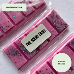 Three pink scented bars in clear plastic packaging with glitter, arranged diagonally on a white textured background. A central label reads 'THE SCENT LABEL' and the image includes text overlays 'LIMITED EDITION' and 'Scented: Chance'.