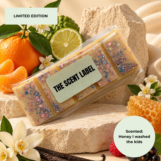 A packaged handmade soap bar labeled 'THE SCENT LABEL' sits on stone blocks with citrus slices, honeycomb, flowers, and vanilla beans around it. Text overlays read 'LIMITED EDITION' and 'Scented: Honey I washed the kids.