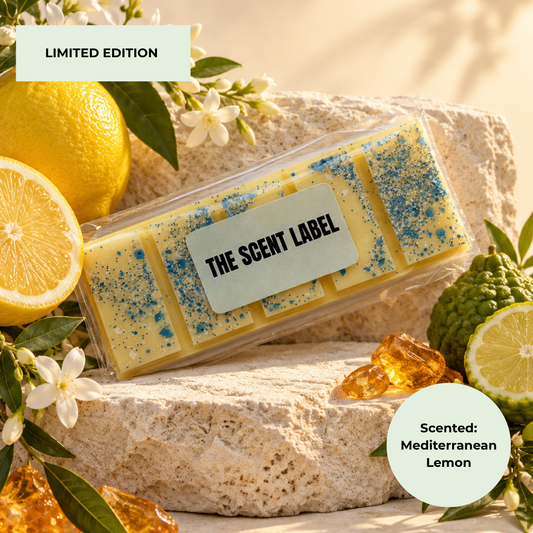 A clear plastic package of rectangular scented bars labeled 'THE SCENT LABEL' sits on a stone surface with lemon halves, flowers, and amber crystals. Text overlays read 'LIMITED EDITION' and 'Scented: Mediterranean Lemon'.